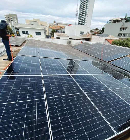 Módulos fotovoltaicos instalados sobre telhado residencial em área urbana.